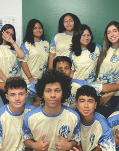 Grupo de estudantes reunidos vestindo uniformes personalizados nas cores azul e branco com estampa lateral de dragão, produzidos pela Maximus Print para turmas de formandos.